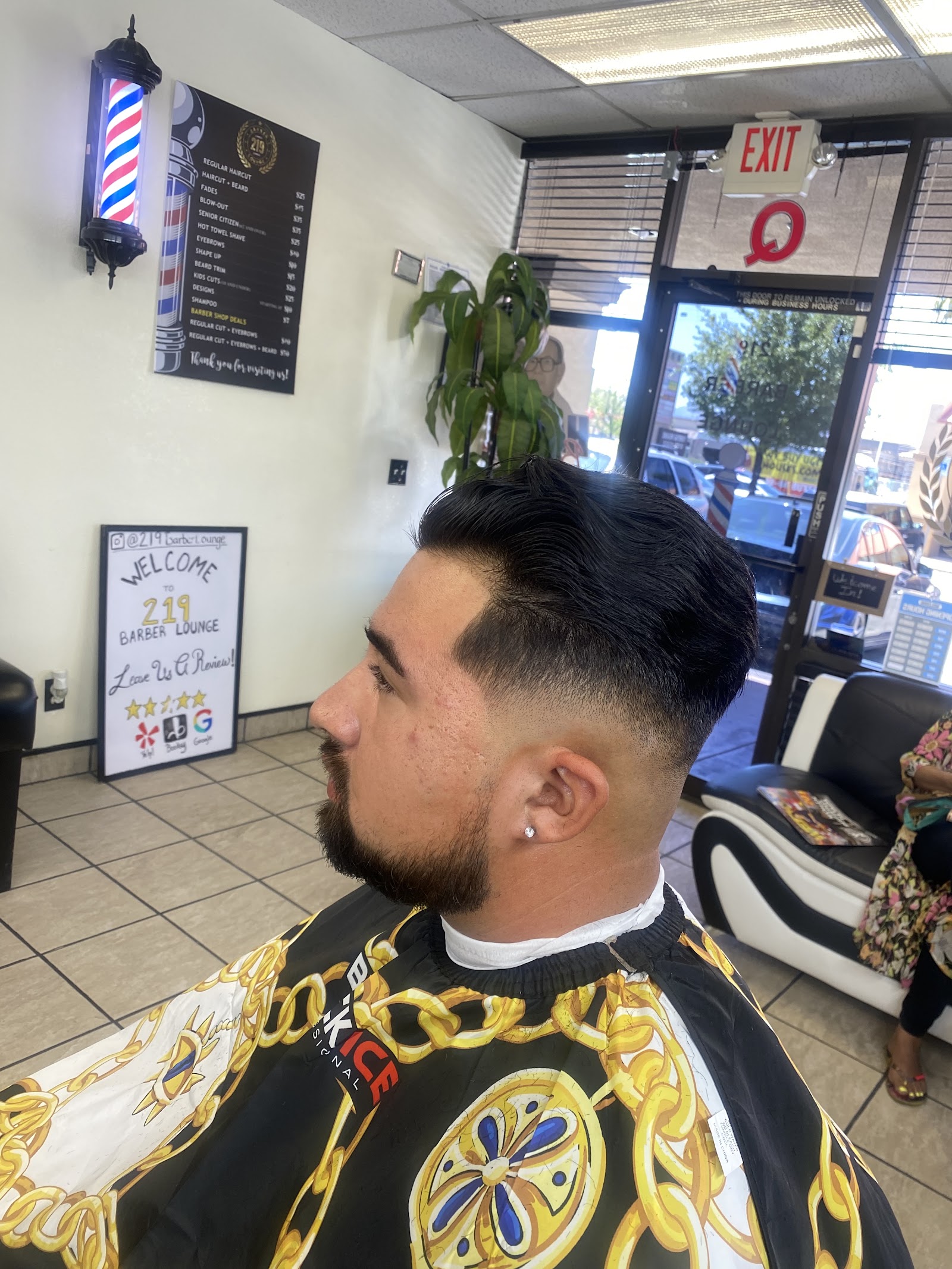 Client with a fresh fade, beard trim and styled top in the barber chair